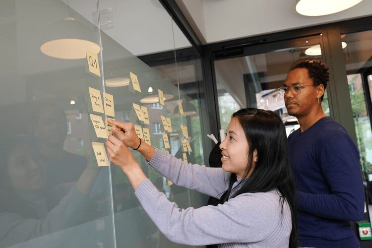 A female product manager putting sticky notes on the wall.
