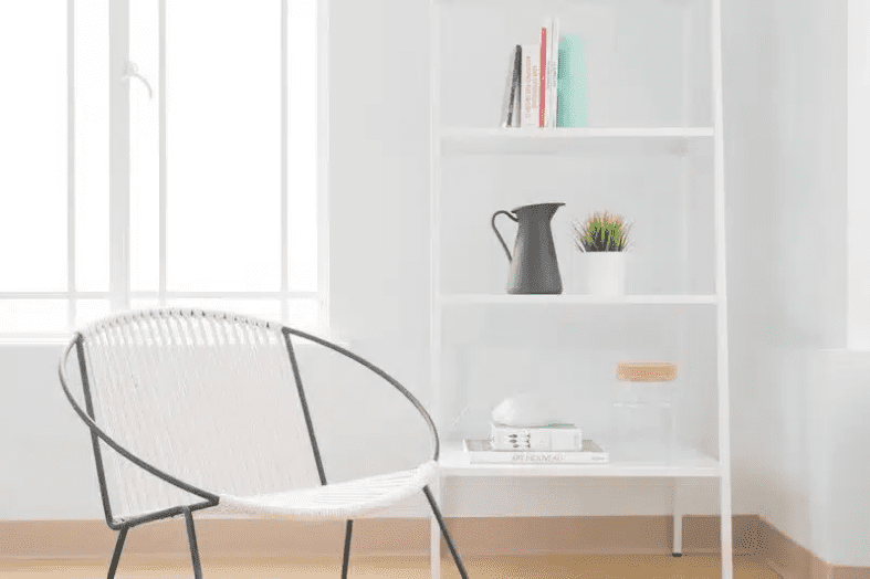 abstract metal and white chair infront of minimalist bookshelf