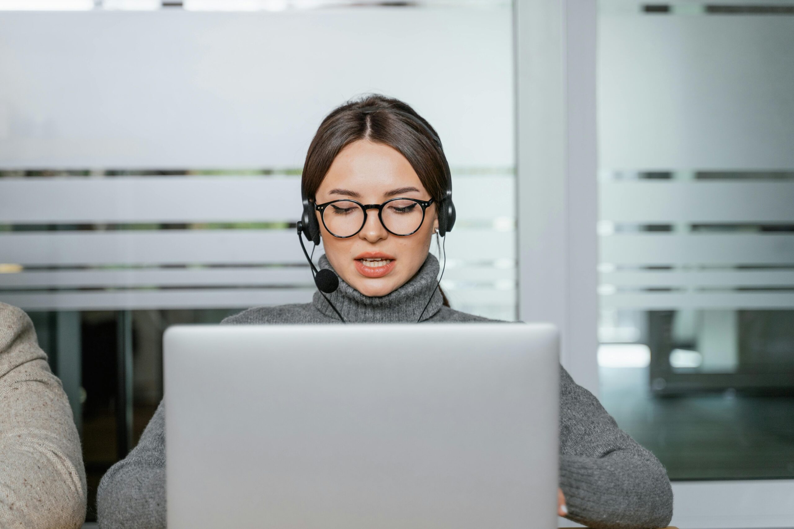 Female working by her laptop with a support headset on.